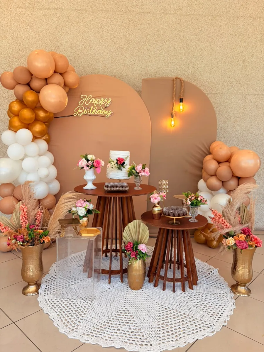 Decoração de festa boho em tons nude e dourado, com balões, painel arco e mesa de bolo